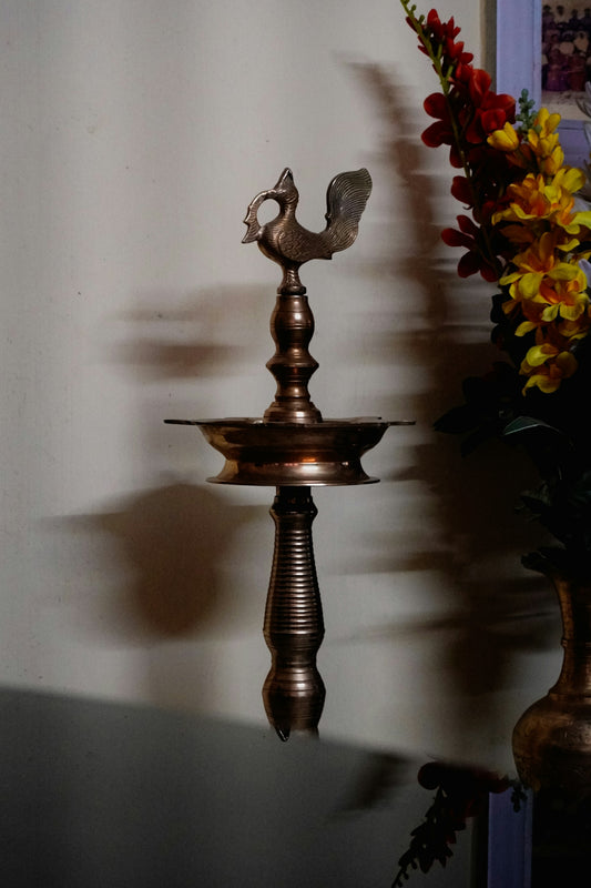 Ornate brass oil lamp with peacock design